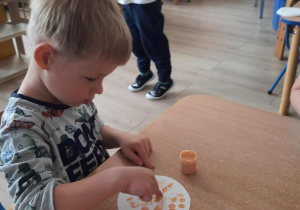 Chłopiec palcem robi kropki na białym kółku.