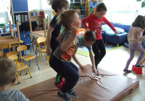 Dzieci skaczą po materacu.
