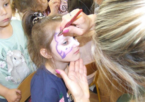 Nauczycielka maluje twarz dziewczynce.