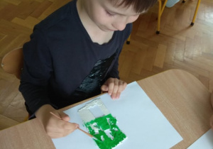 Chłopiec maluje obrazek z gliny.