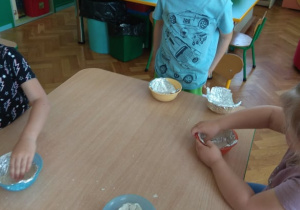 Dzieci bawią się masą z gliny.