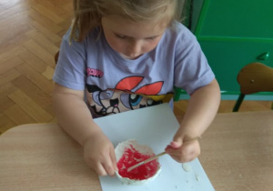 Dziewczynka maluje masę z gliny.