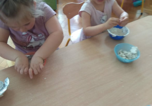 Dzieci bawią się masą z gliny.