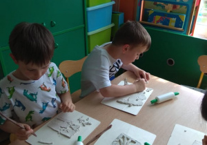 Dzieci wykrawają obrazki z gliny.