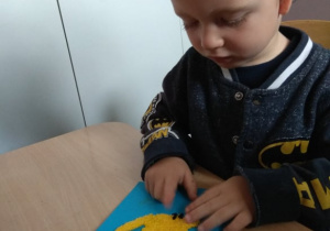 Chłopiec wykleja obrazek masą piankową.