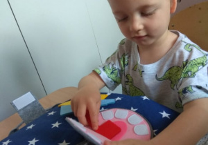 Chłopiec bawi się książeczką sensoryczną.