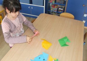 Dziewczynka składa origami - kot i pies.