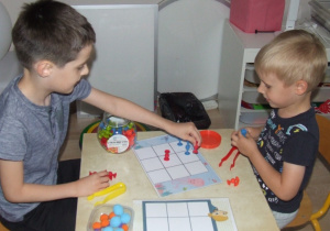 Chłopcy z użyciem klocków z przyssawkami gra w kółko i krzyżyk.