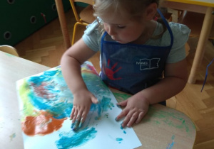 Dziewczynka maluje farbami.