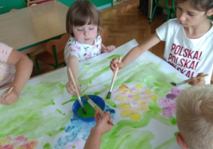 Dzieci malują wiosenną łąkę.