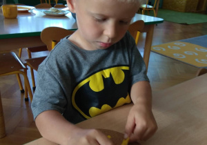 Chłopiec naciąga gumki recepturki na pinezki.