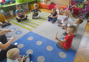 Dzieci wystukują rytm na pałeczkach.