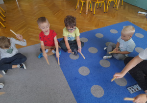 Dzieci wystukują rytm na pałeczkach.
