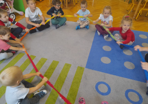 Dzieci siedzą na dywanie z gumą animacyjną.
