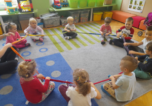Dzieci siedzą na dywanie z gumą animacyjną.