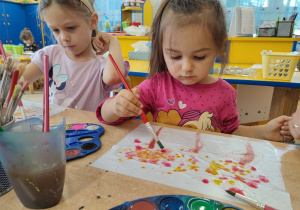 Dziewczynki malują farbami jesienne pejzaże.