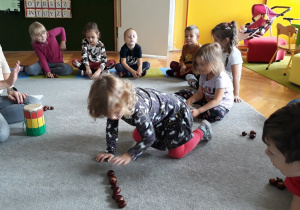 Dzieci układają węża z kasztanów.