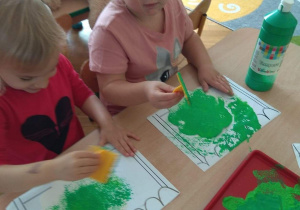 Dzieci stemplują zieloną farbą.