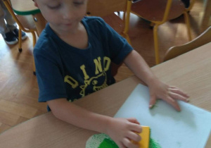 Chłopiec stempluje zieloną farbą.