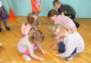 Dzieci zbierają piórka z podłogi.