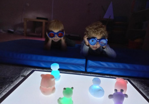 Dzieci obserwują świecące zabawki przez okulary.