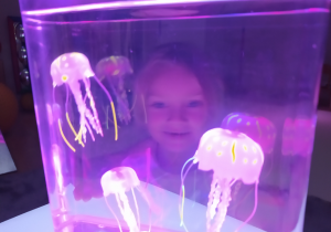 Dziewczynka ogląda świecące meduzy.