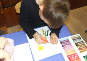 Chłopiec maluje mniszki.