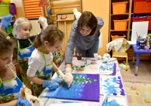 Dzieci pomagają malować obraz.