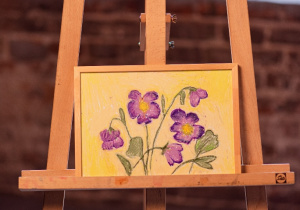 Obraz przedstawiający kwiaty na sztaludze.