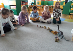 Dzieci oglądają figurki dinozaurow.