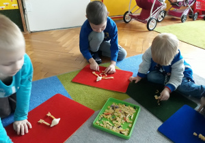 Dzieci układają z makaronu na kolorowych podkładkach.