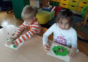 Dzieci układają z makaronu na kolorowej plastelinie.