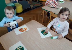Dzieci układają z makaronu na kolorowej plastelinie.