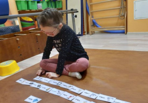 Dziewczynka siedzi na materacu i układa litery.