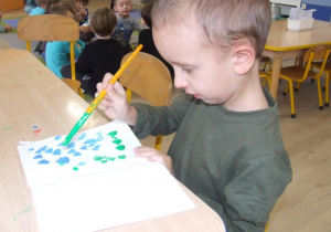 Chłopiec maluje plamy.