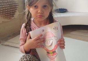 Dziewczynka naśladuje minę narysowaną Mikołajowi.