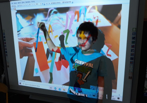 Chłopiec pokazuje pasek papieru na tle slajdu z paskami papieru.
