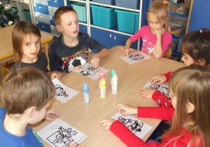 Dzieci malują farbami świąteczne ilustracje.