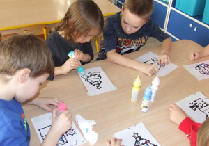 Dzieci malują farbami świąteczne ilustracje.