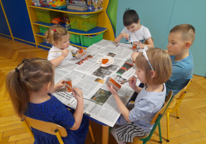 Dzieci malują rolki farbami.