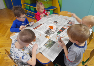 Dzieci malują rolki farbami.