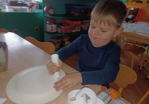 Chłopiec przykleja łańcuch do talerza papierowego