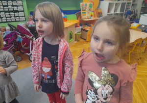 Dziewczynki wykonują ćwiczenia narządów mowy.