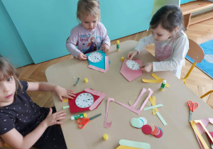 Dzieci przyklejają elementy tworząc zegar.