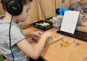 Chłopiec układa wzory z wykorzystaniem kolorowych gumek.