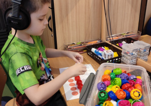 Chłopiec układa wzory z wykorzystaniem kolorowych korków.