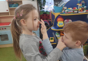 Dzieci głaskają sie po nosie.