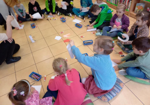 Dzieci wykonują bałwanka z papieru.