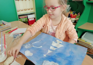 Dziewczynka tworzy zimowy obraz.