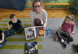 Nauczycielka pokazuje książki o kosmosie.